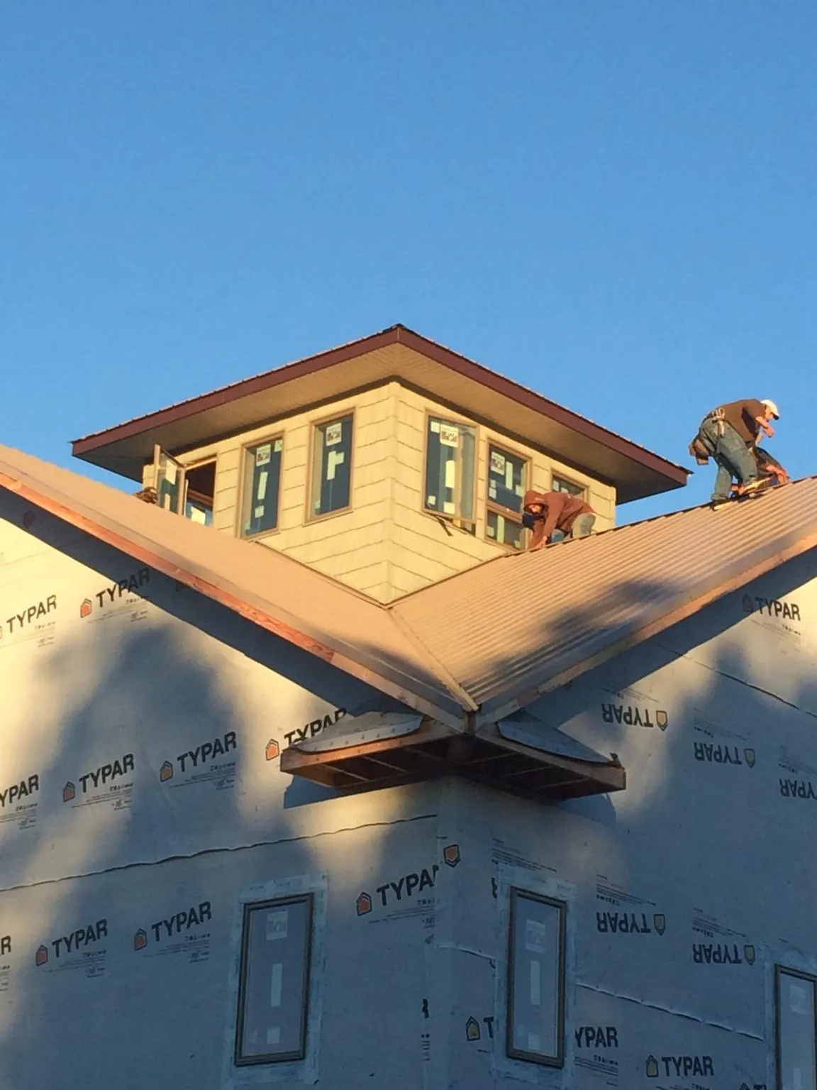 Roofers working around a rooftop cupola on a new metal roof at sunset — Roof Waterproofing in Hopedale by Roofing Brothers